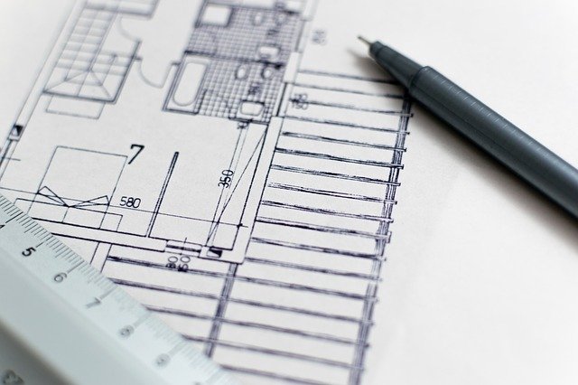 Pen and ruler on paper with building plans drawn on. 