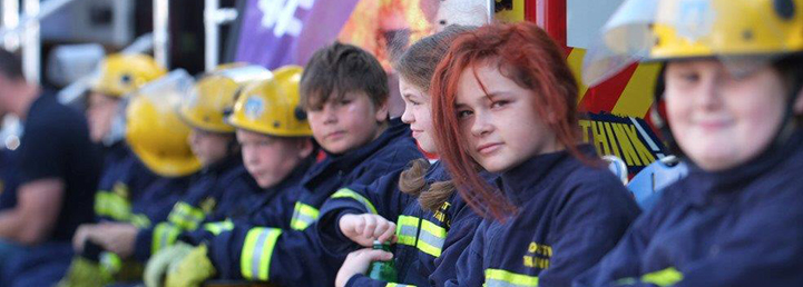 Young people sat down wearing fire kit.