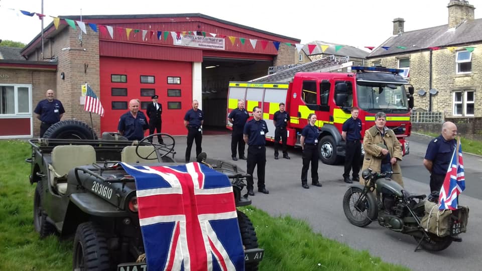 Firefighters stood outside fire station alongside military personnel and union jack flags .
