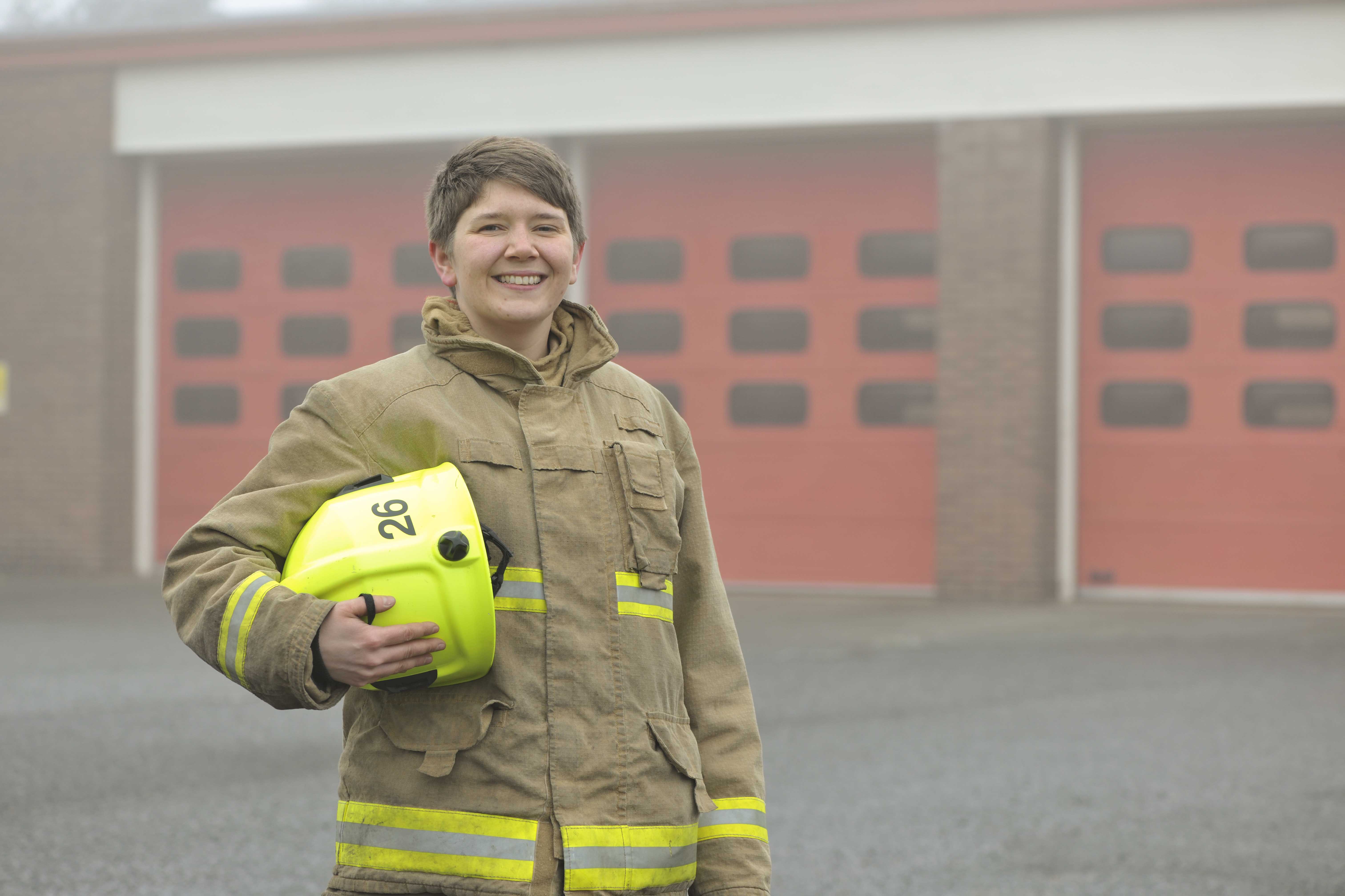 Firefighter stood in front of fire engine. 