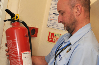 Fire Protection Inspector looking at a fire extinguisher.