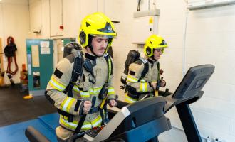 Two firefighters, in full BA kit, on a treadmill